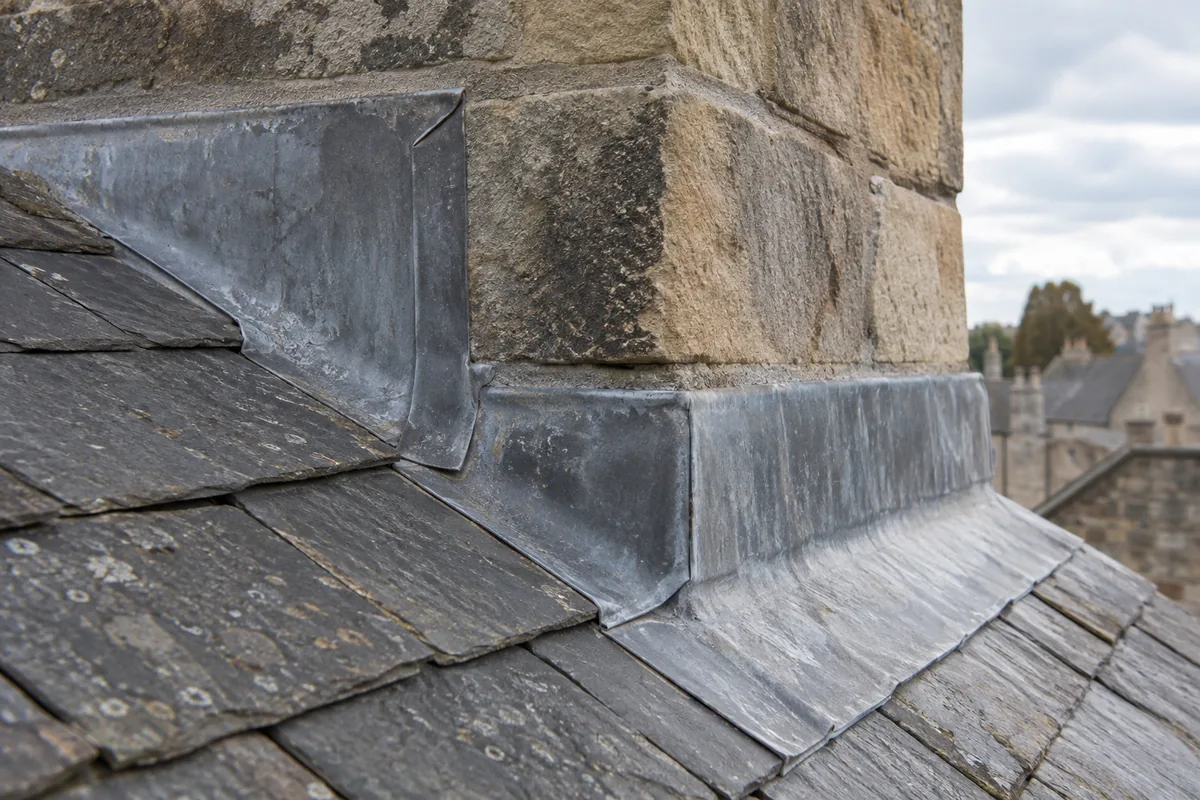 Illustrative lead apron and side flashing around the base of a stone chimney.