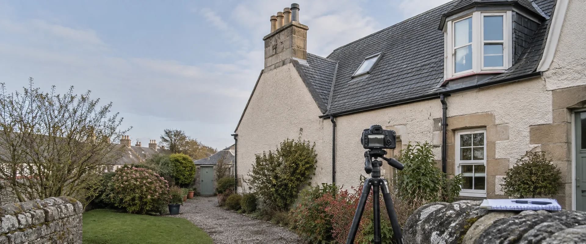 Illustrative camera and inspection notebook set up to examine a slate-roofed house.