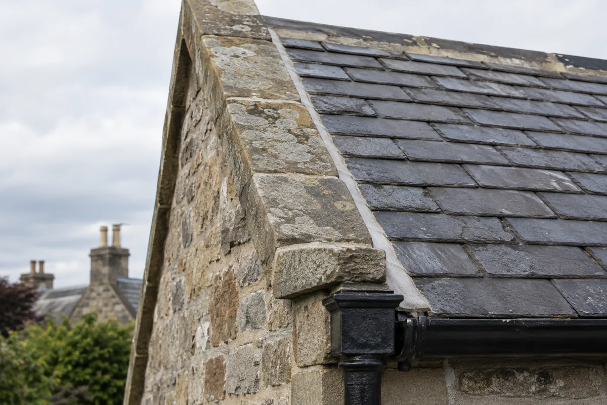 Illustrative stone-coped verge, slate edges and gutter termination.
